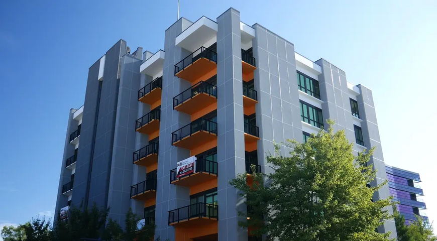 Apartment building using white and gray Dryvit panels with orange balcony on Pacific Avenue sign in the foreground